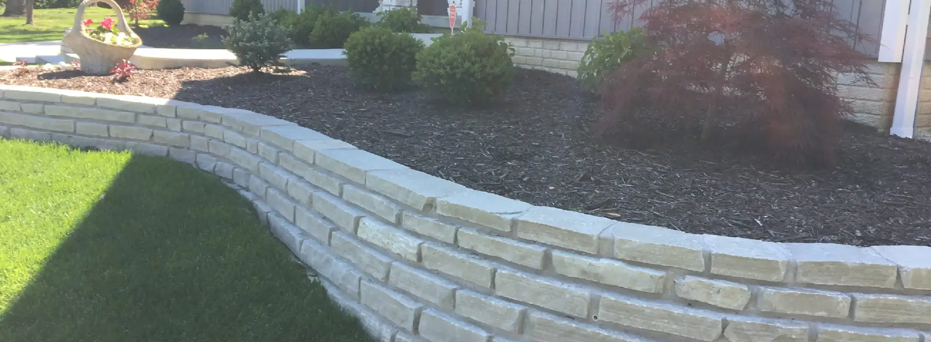 A retaining wall along a planting bed of a front yard, designed by Mark Hoerr Landscaping