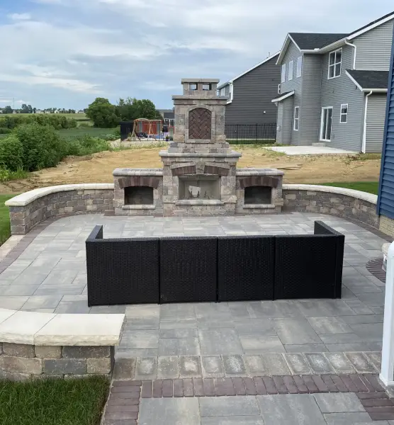 An outdoor patio with a stone fireplace, part of the outdoor living solutions provided by Mark Hoerr Landscaping in Peoria, IL