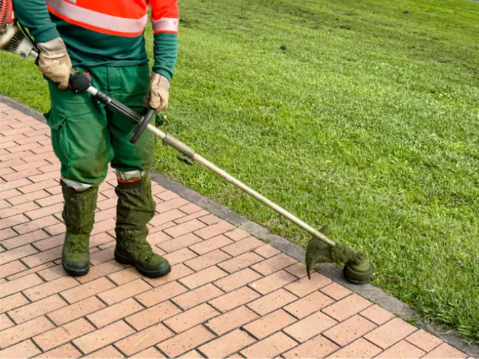 A landscaper cutting weeds along recently installed edging by Mark Hoerr Landscaping