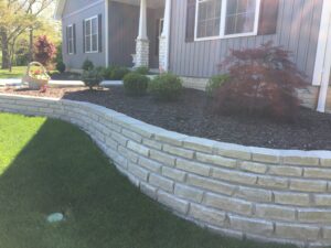 Landscaper in Washington IL showcasing front yard landscaping with new retaining wall.