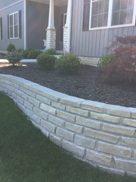 Landscaper in Washington IL showcasing front yard landscaping with new retaining wall.